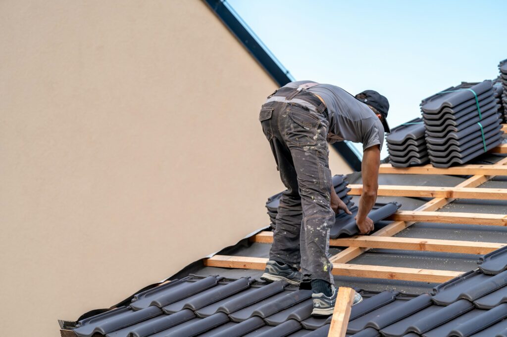 roofer installs a fired ceramic tile on the roof of family house